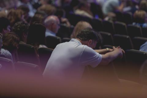 Man with head bowed in prayer during a worship service by TWUMC | Lightstock | Used by Permission