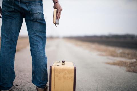 Man staring down a road holding a Bible next to a suitcase by Pearl | Lightstock | Used by Permission